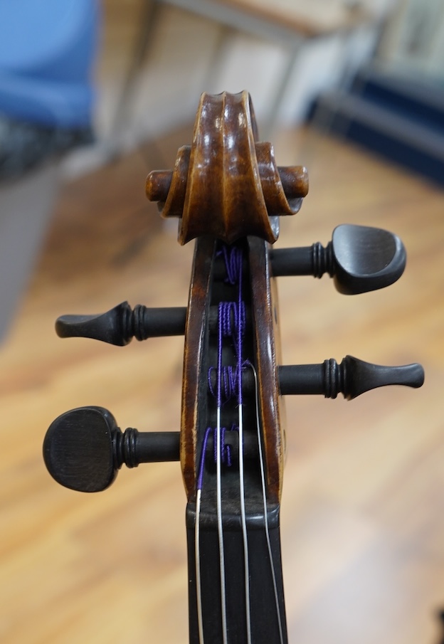 An early 20th century German violin, with a label reading ‘Copy of Joseph Guarnerius, Made in Germany’, body length 35.5cm, cased with a bow by Tourte. Condition - good.